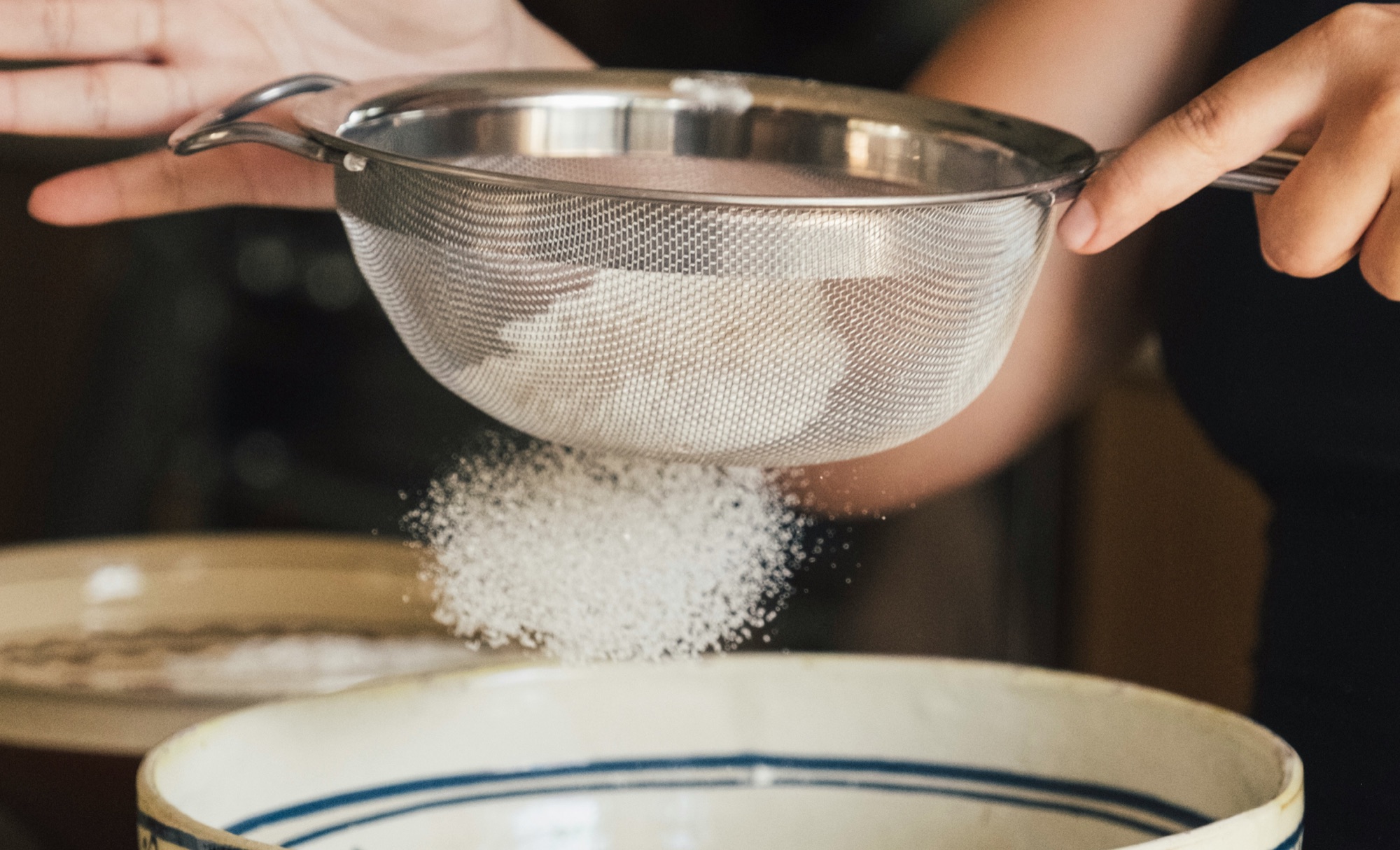 farine qui passe à travers un tamis au-dessus d'un bol